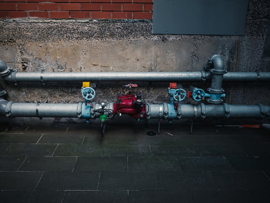 A detailed view of industrial pipes with colorful valves on a textured wall.
